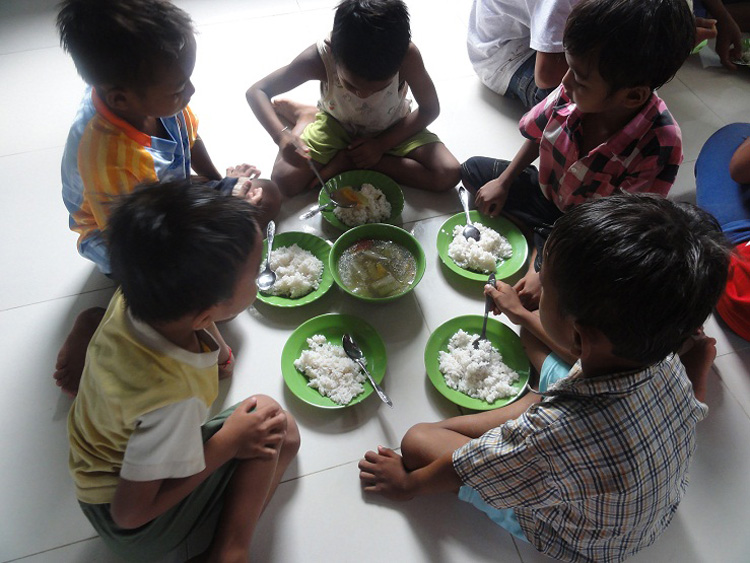 Kinder und Volontäre beim Mittagessen
